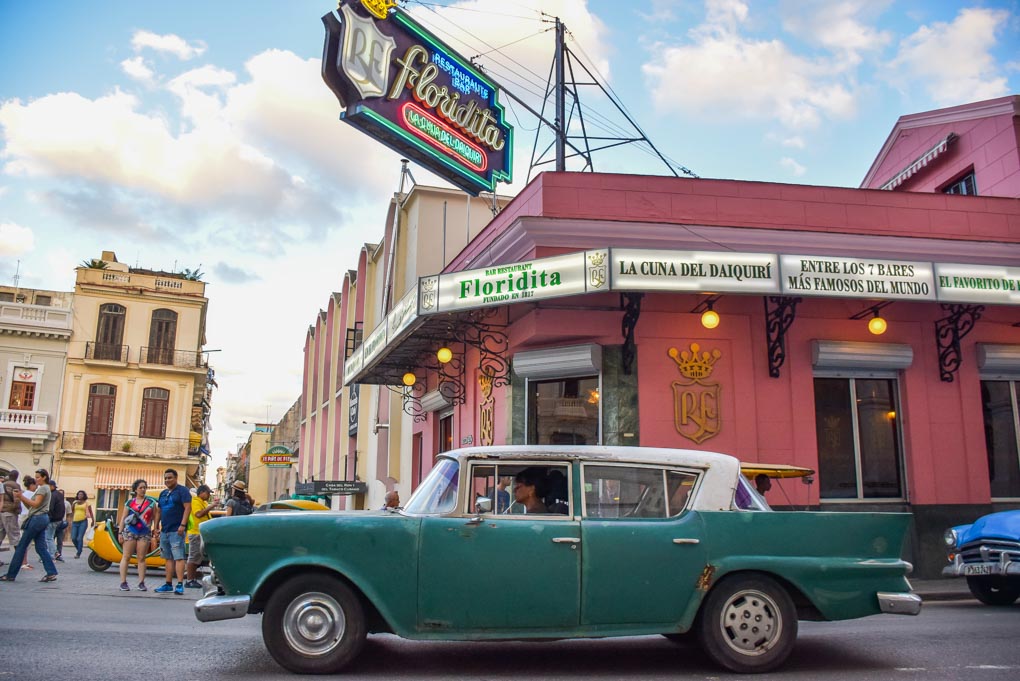 An old car drives past the La Bodeguita del Medio bar in Havana