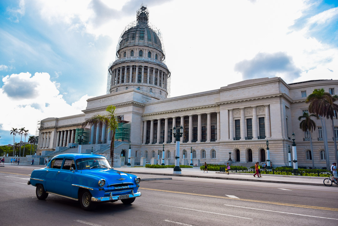 the capital building in Havana cuba with a blue vintage car in front