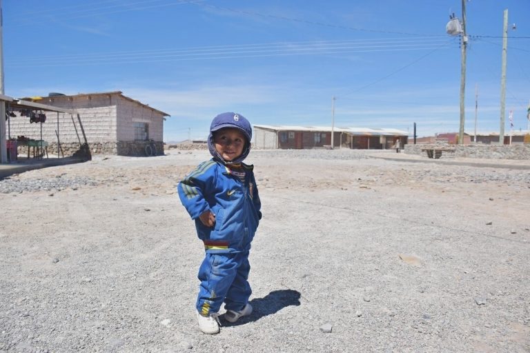 a cute kid posing for the camera on the slat flats in bolivia