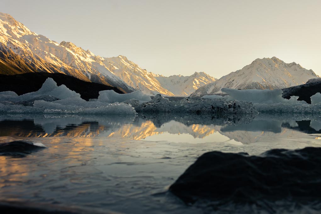 The Tasman Glacier and Tasman Lake just as the sun appears behind the mountains