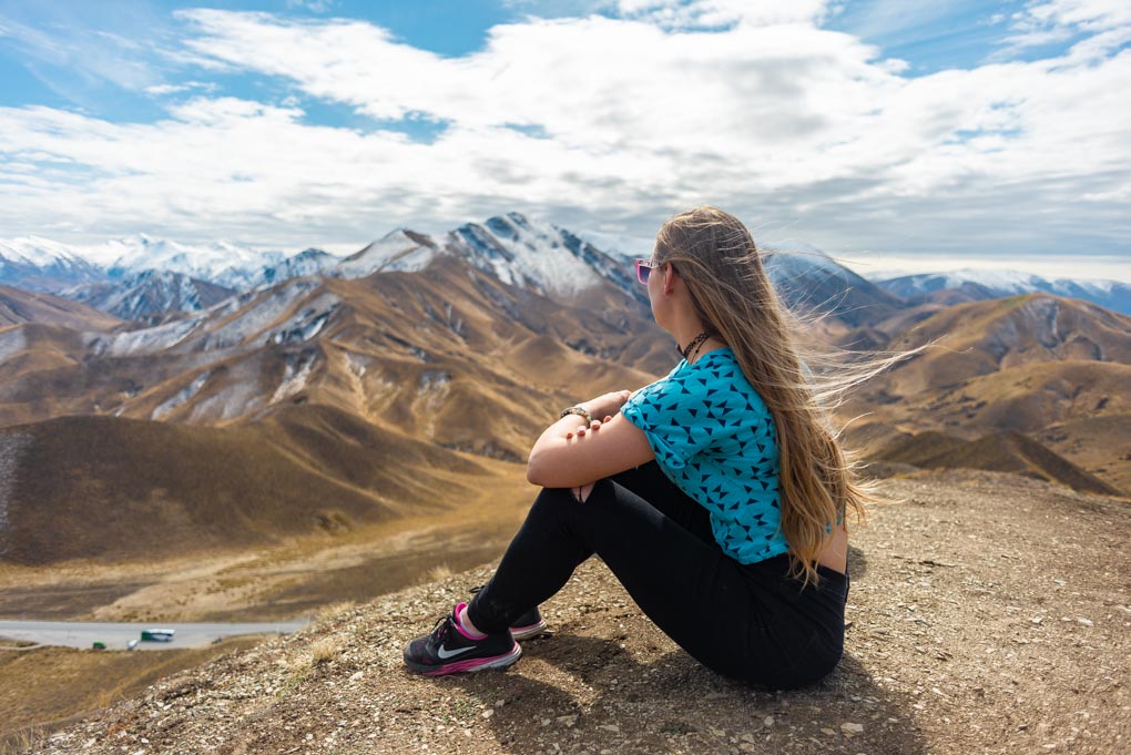 Bailey sits down and looks out at Lindis Pass, New Zealand