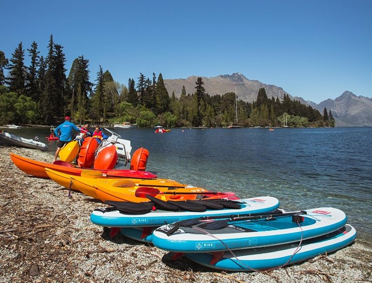 Paddel boards and kayaks on the shore of Lake Wakatipu during a Queenstown summer