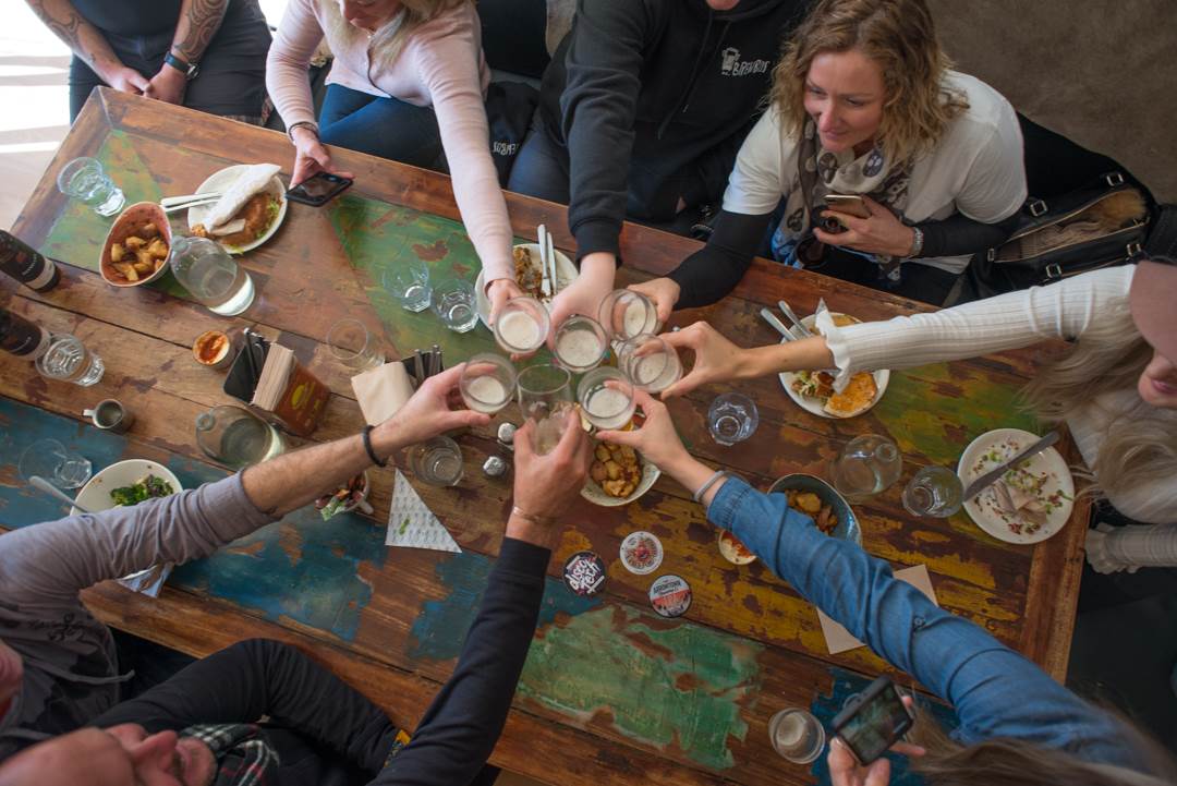 People cheers each other on a table at a brewery in New Zealand on a craft beer tour