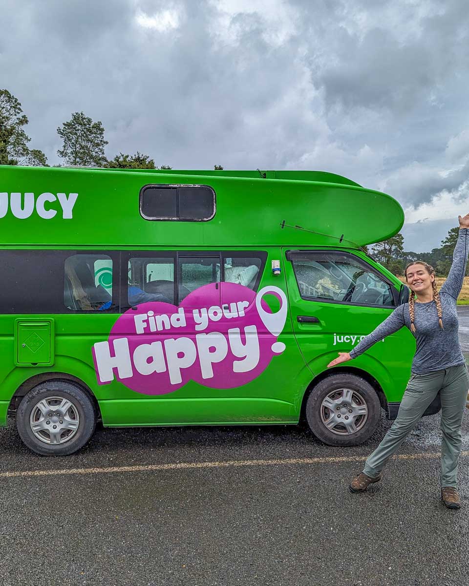 Bailey stands infront of a JUCY campervan in New Zealand