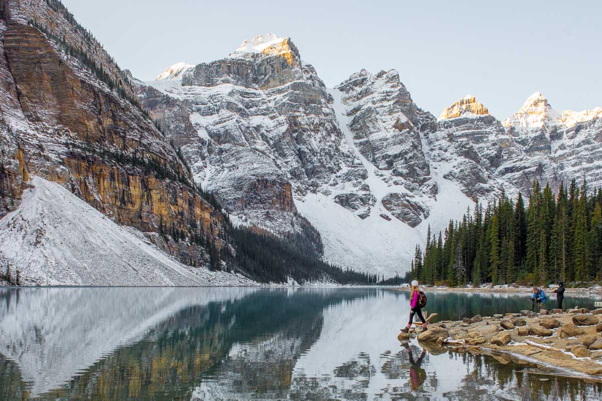 Bailey walks on the shoreline on Moraine Lake in Banff at sunrise