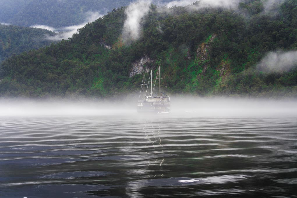 A boat cruises through Doubtful Sound in New Zealand