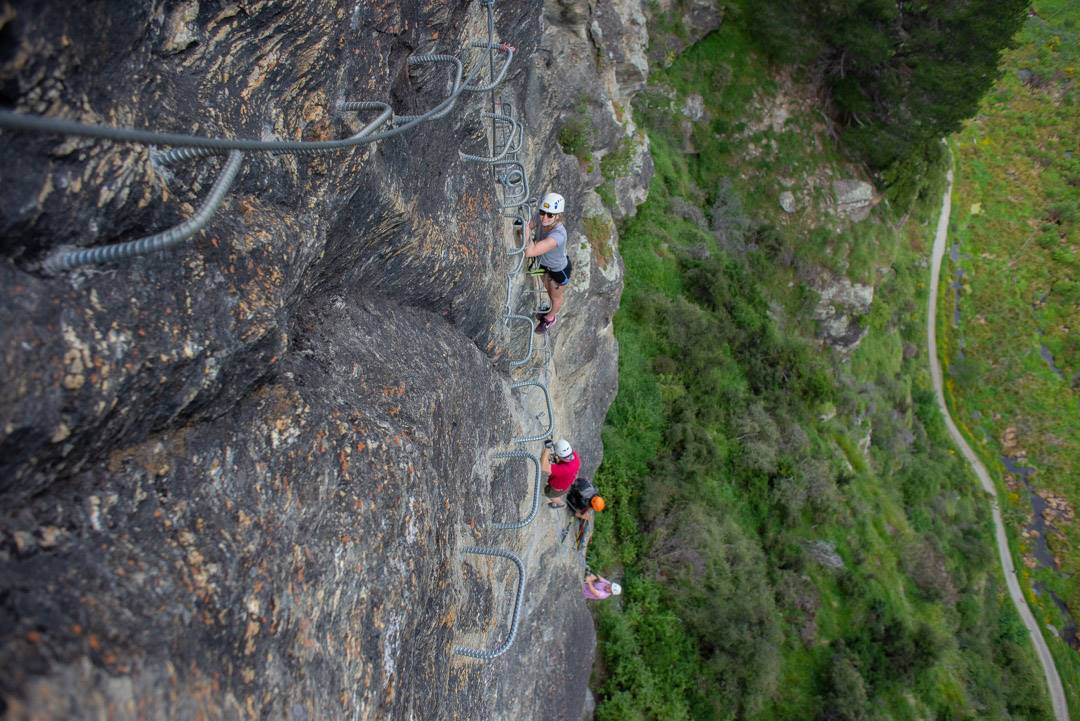people on a cliff doing Via Ferrata