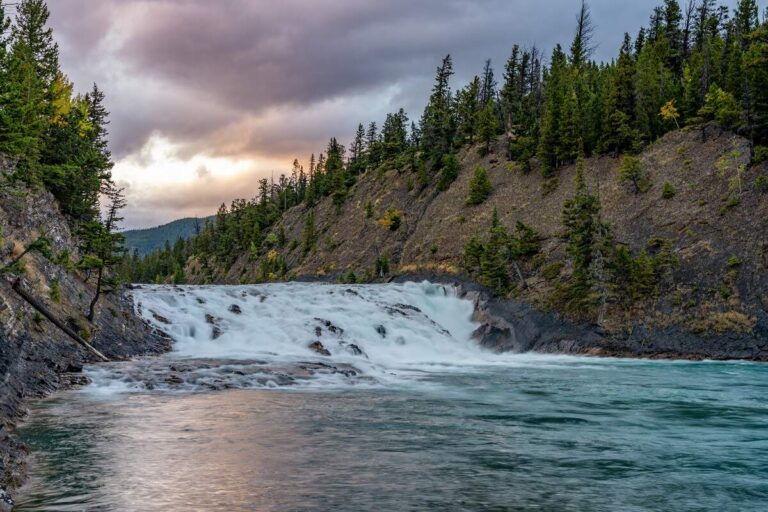view of Bow Falls in Banff from the river's edge during sunset