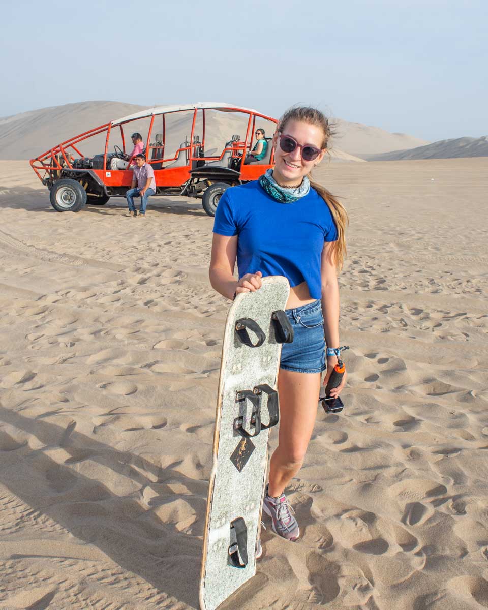 Bailey poses with the dune buggy and sandboard in Huacachina after using Peru Hop to get around!