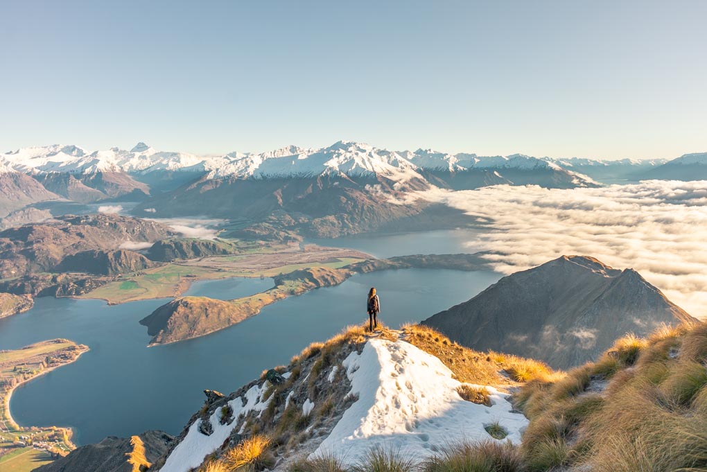 Bailey stands on Roy's Peak, New Zealand at sunrise