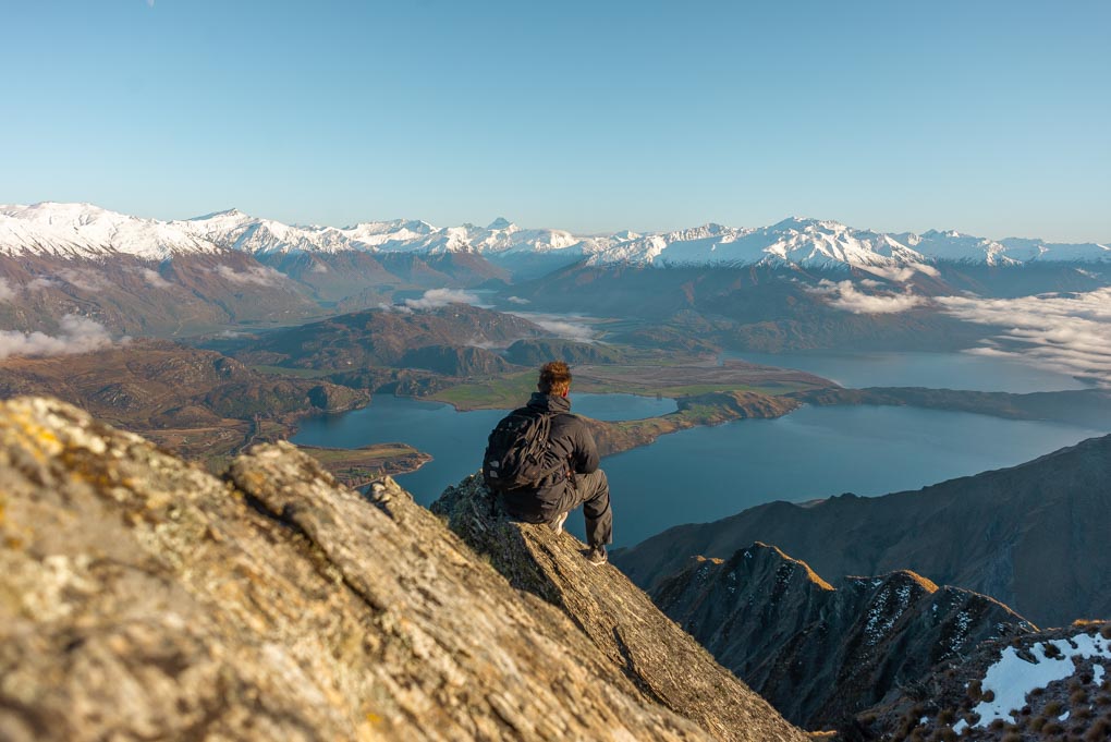 A man sits on a rock at Roy's Peak and enjoys the views