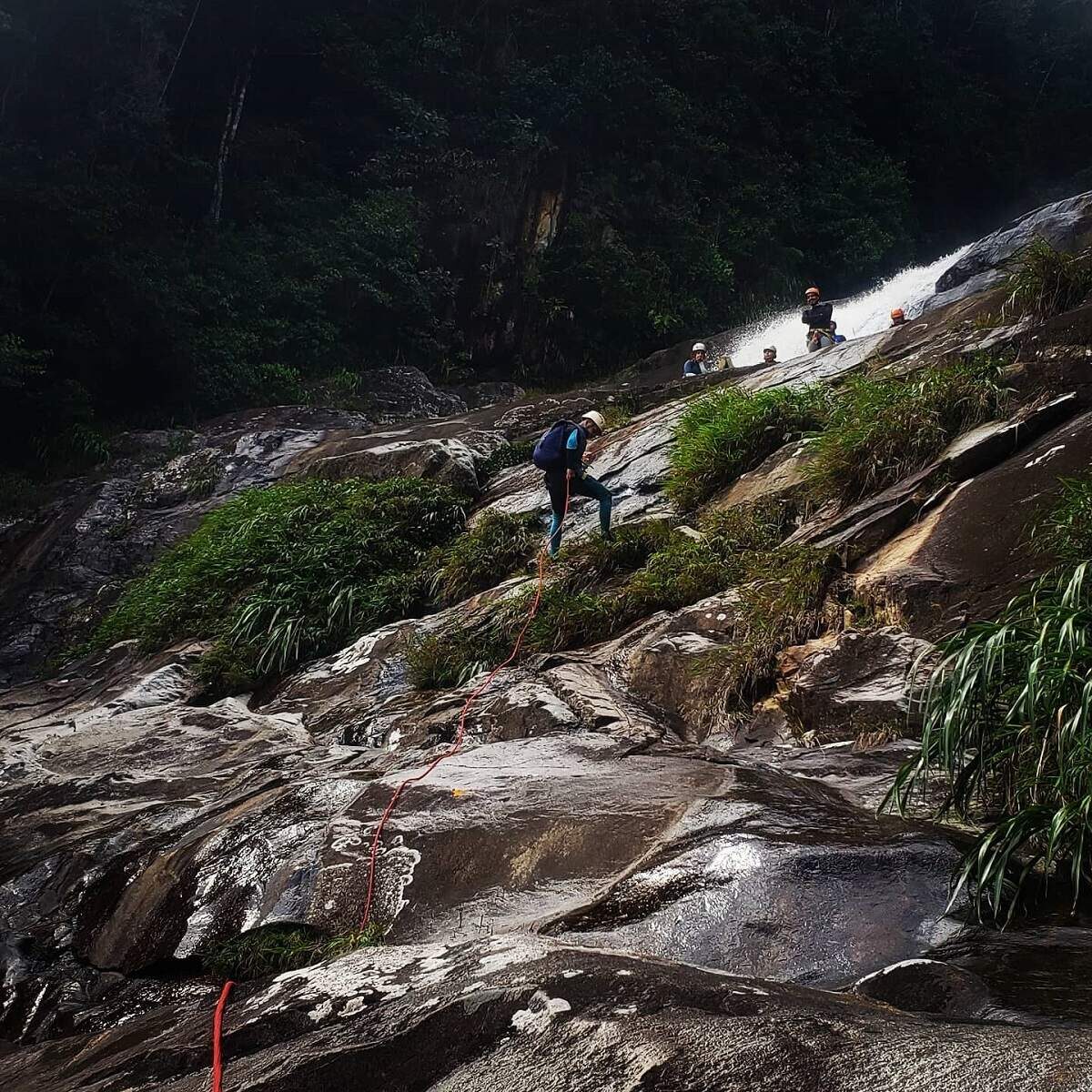 person repelling down a slippery rock wall near Guatape