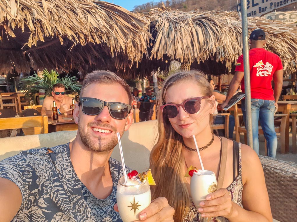 Bailey and Daniel drink cocktails as the sun sets