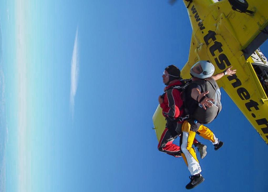 A person leaves the plane on a skydive in the Bay of Isalnds.