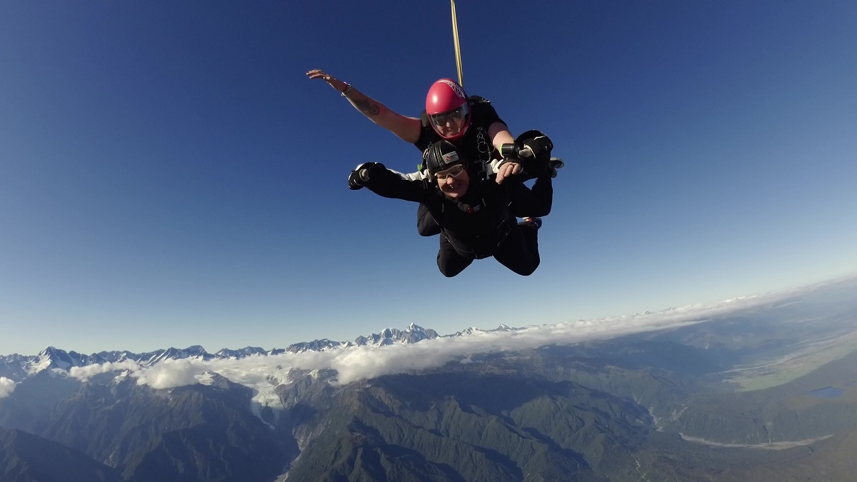 two people skydiving over mountains in Franz Josef