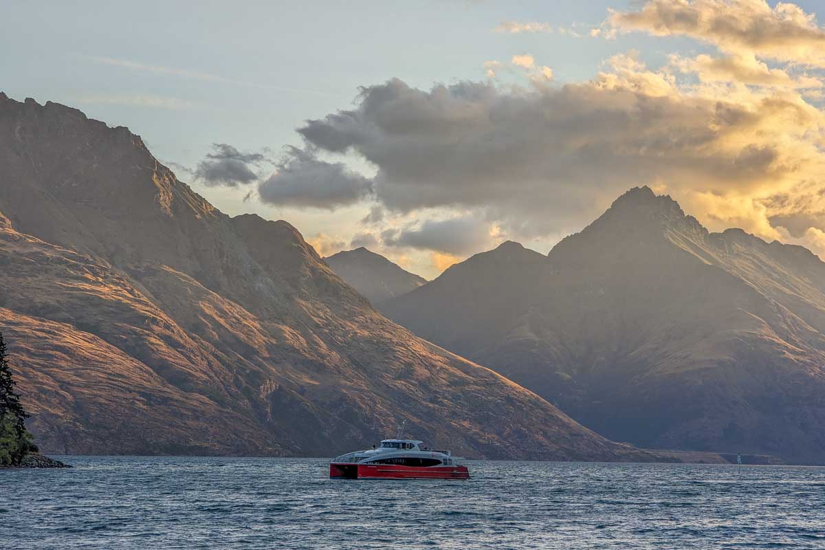 A boat cruises lake Wakatipu at sunset