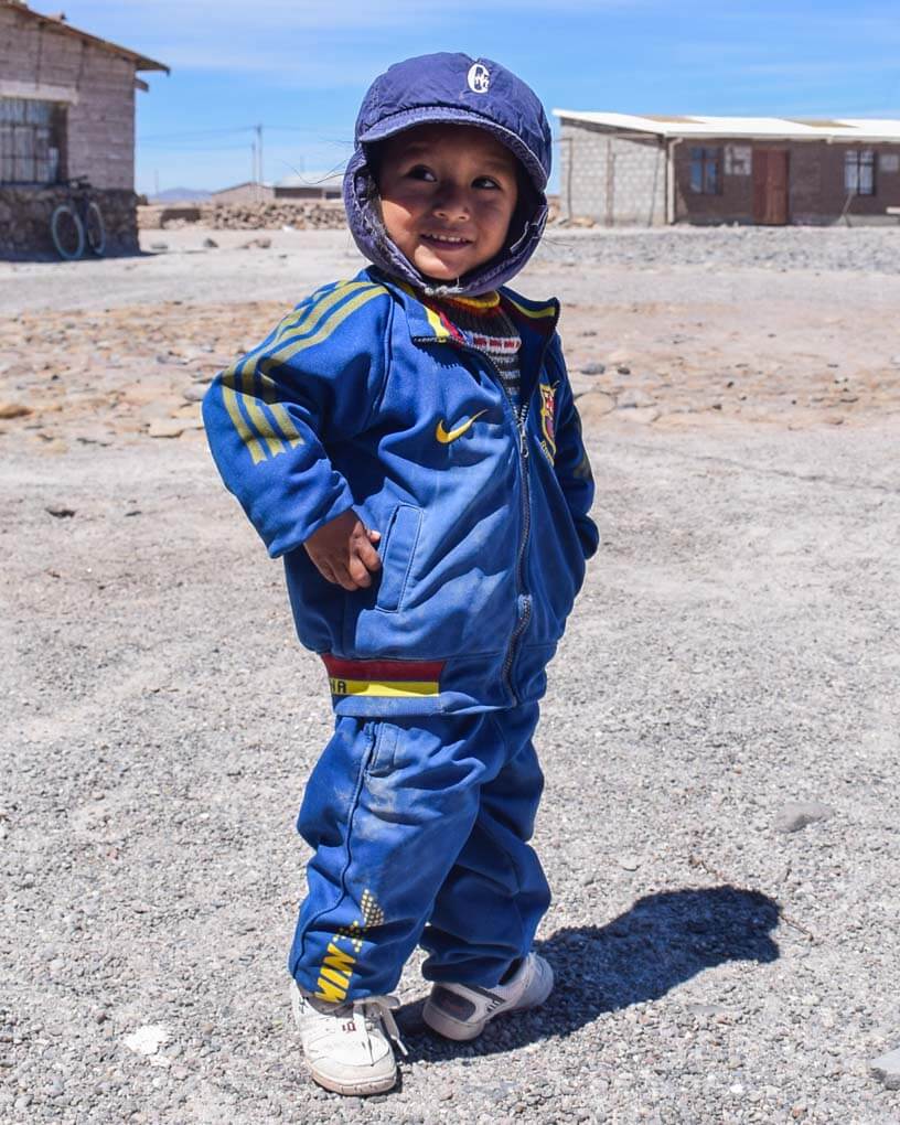 A child poses for a photo at a ssalt mining town on te salt flats of Bolivia