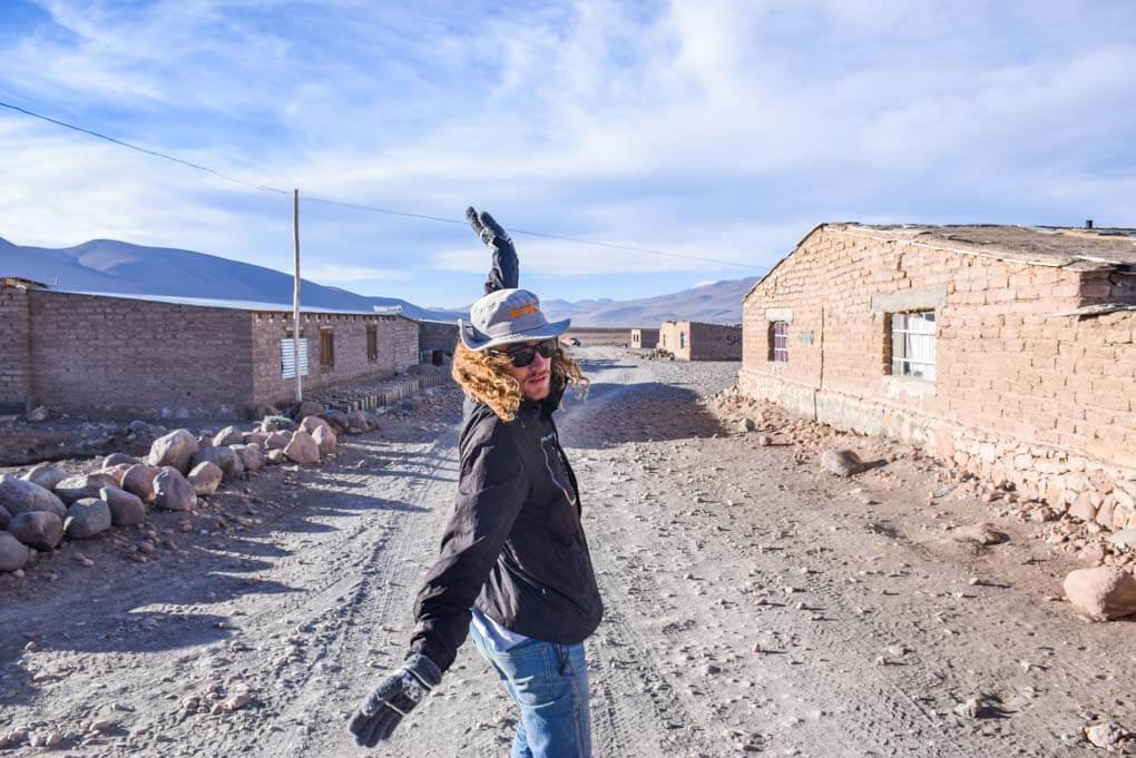 A man makes a silly pose while in one of the towns in the salt flats. Here you can buy food.