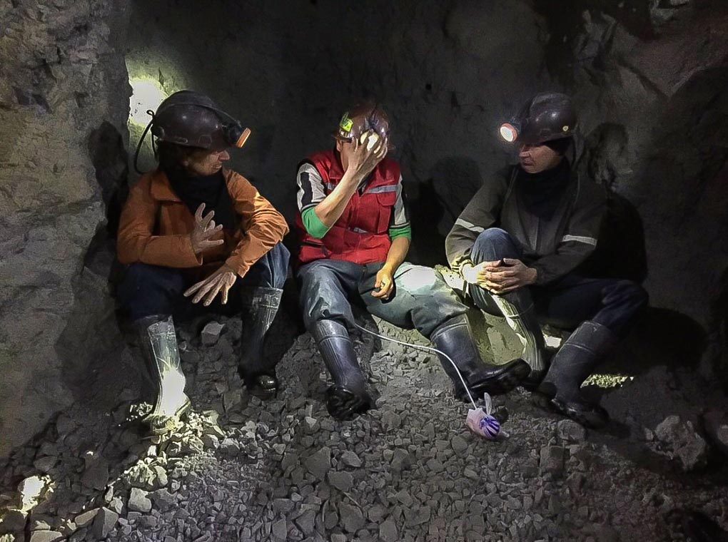 Three men sit in the Cerro Roco mine in Potosi, Bolivia