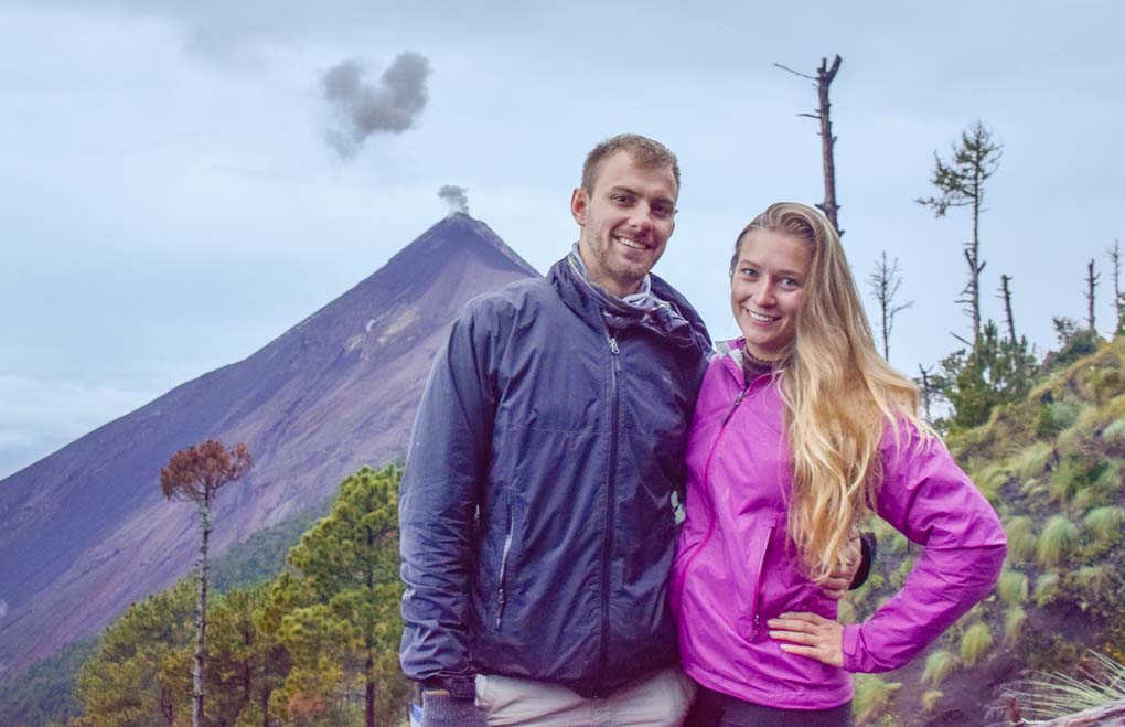 Bailey and Daniel take a photo with Fuego volcano erupting in the background along the acatenango volcano hike