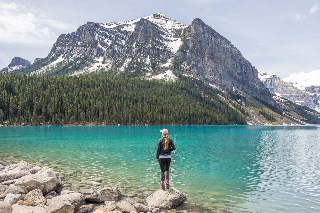 A lady stands at the Lake Louise forshore