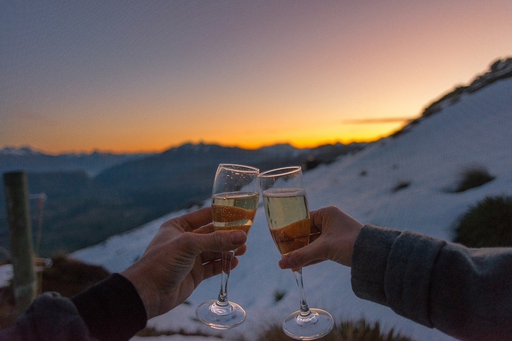 two glasses cheers at sunset on a mountain during a honeymoon holiday in New Zealand