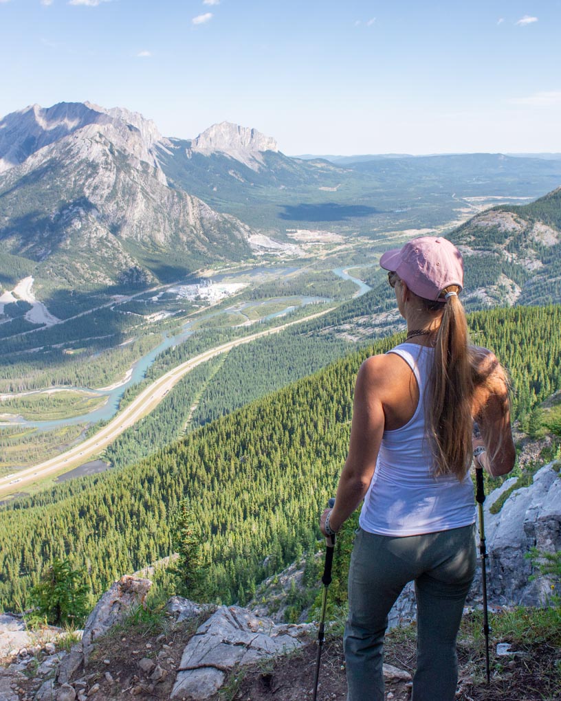 A lady stands with her hiking poles looking at the views from the Heart Mountain trail