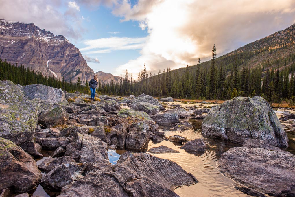 A lady climbs rocks at the end of the Consolation Lakes Trail