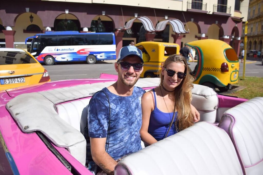 sitting in a hot pink vintage car in Havana, Cuba