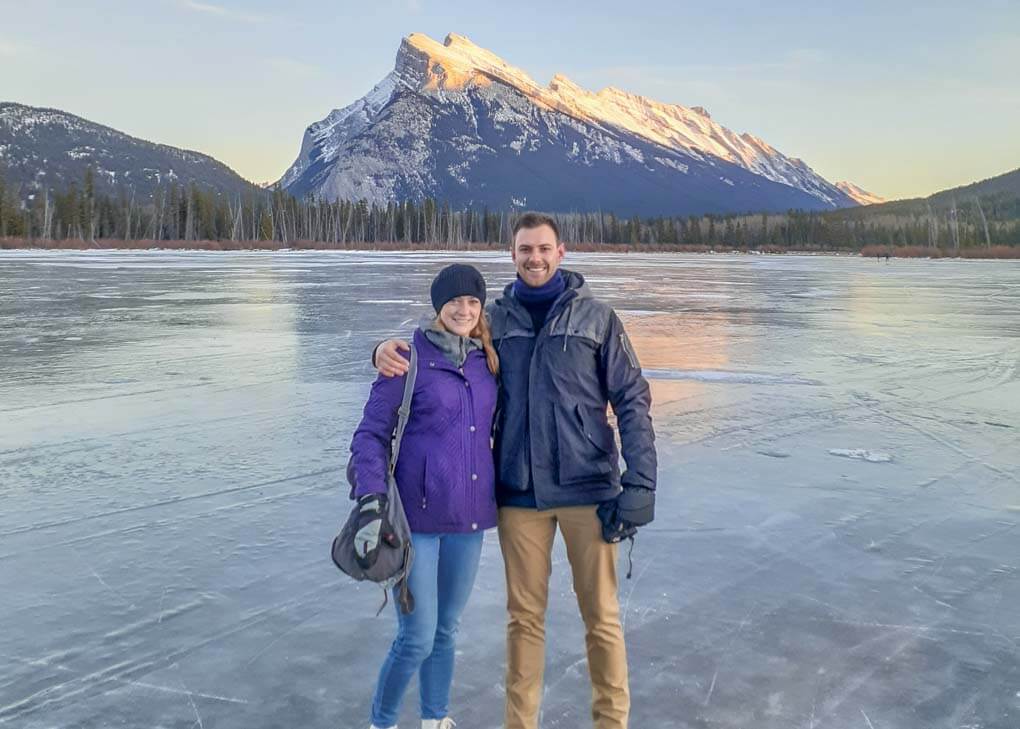 Bailey and Daniel from Destinationless Travel pose for a photo on a frozen lake