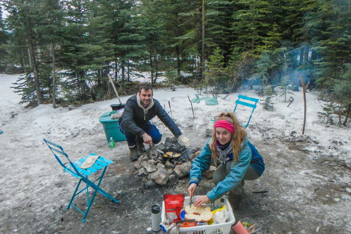 Bailey and Daniel cooking on a fire in the snow winter camping