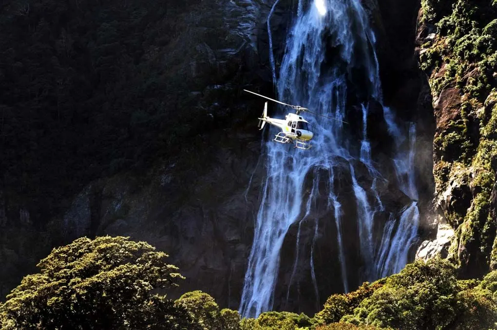 A helicopter flies though Milford Sound, New Zealand