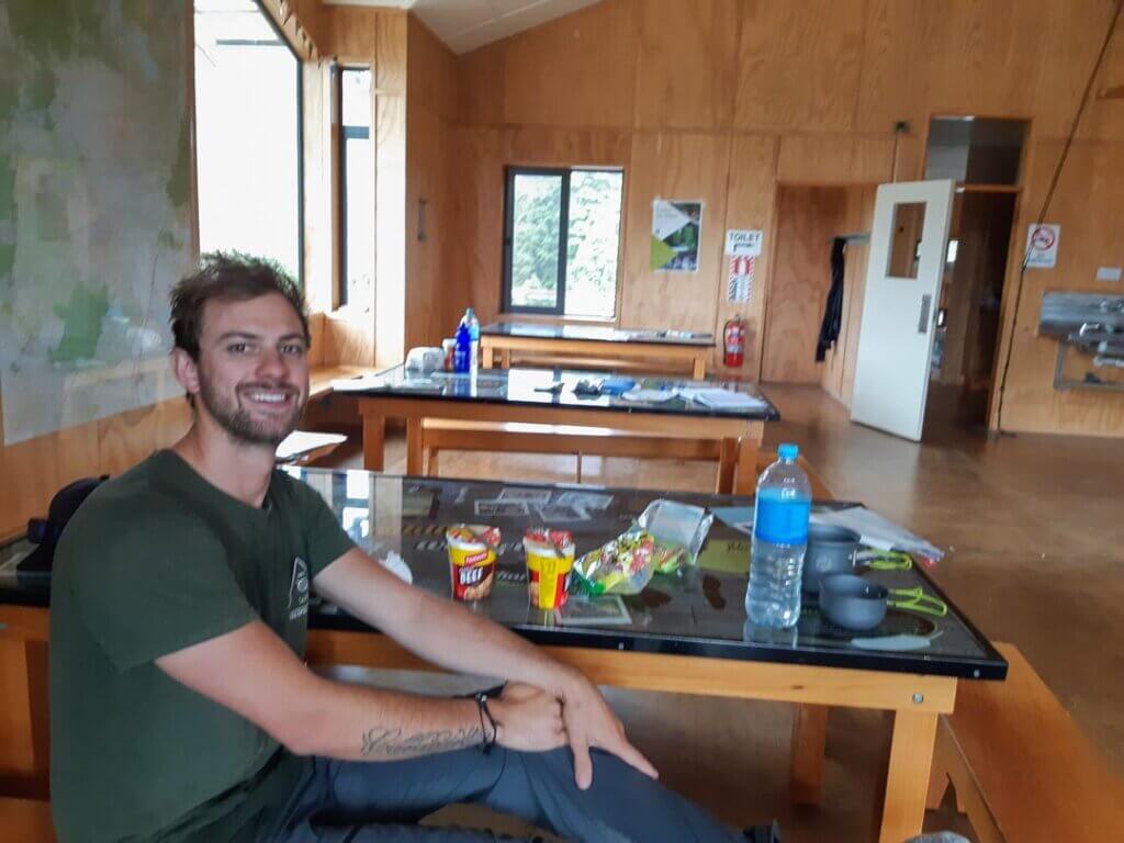 Daniel sitting at a table at the Waihohonu Hut