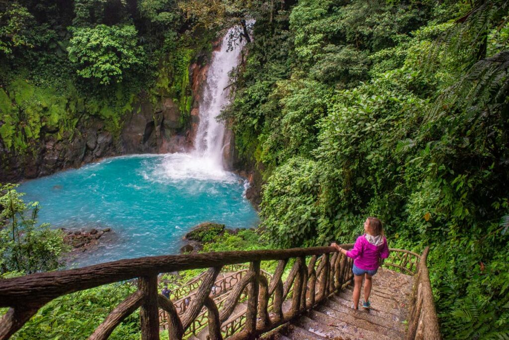 A lady walks down the stairs to Rio Celeste Waterfall