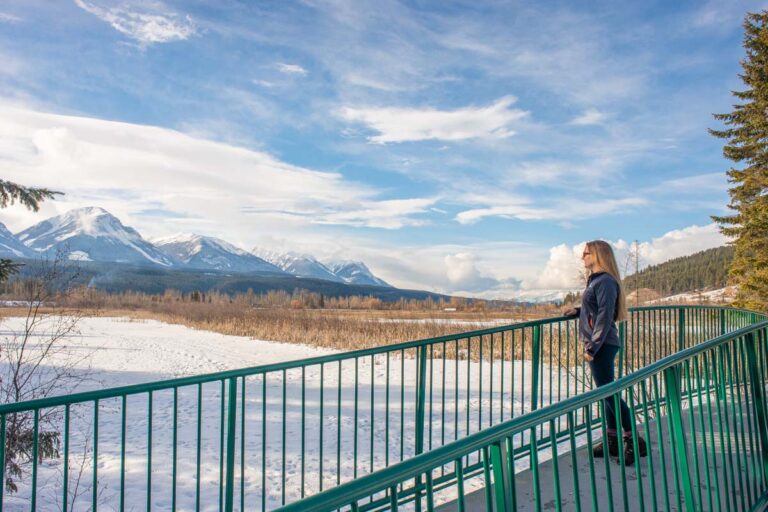 A lady stands on a bridge at Beaver Lakes in Golden, BC in winter