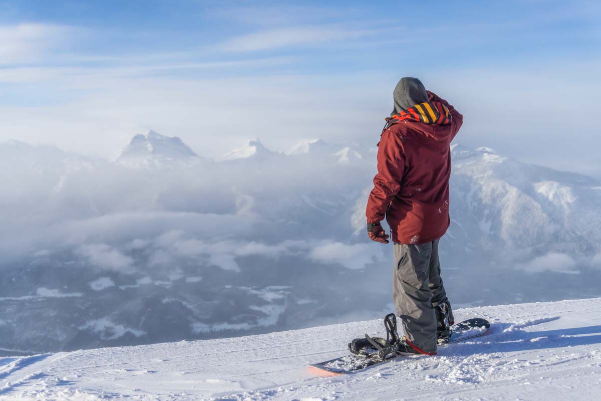 A snowboarder stands at the top of Revelstoke Mountain Resort in BC, Canada during winter
