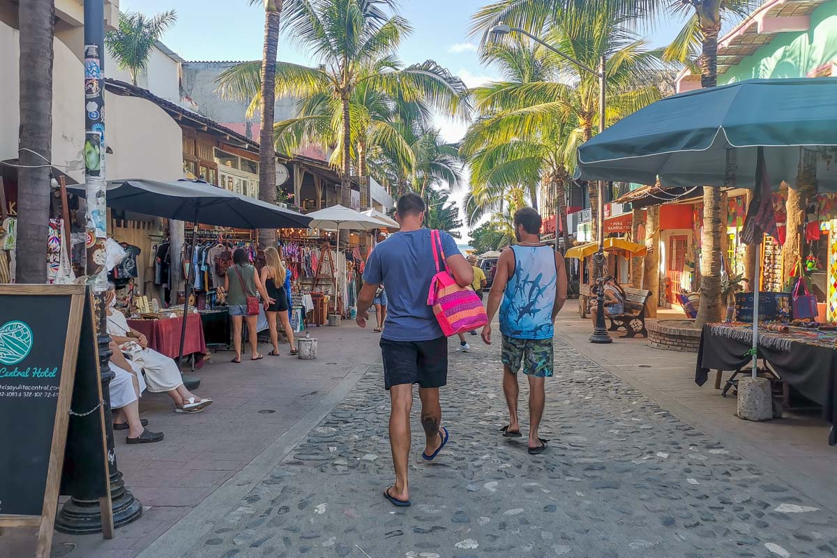 two men walking down a busy street in downtown Sayulita