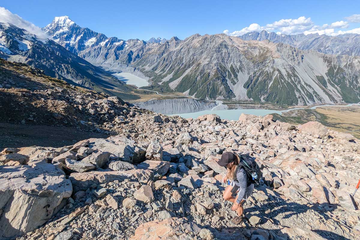 A lady hikes along a rocky area towards the Mueller Hut