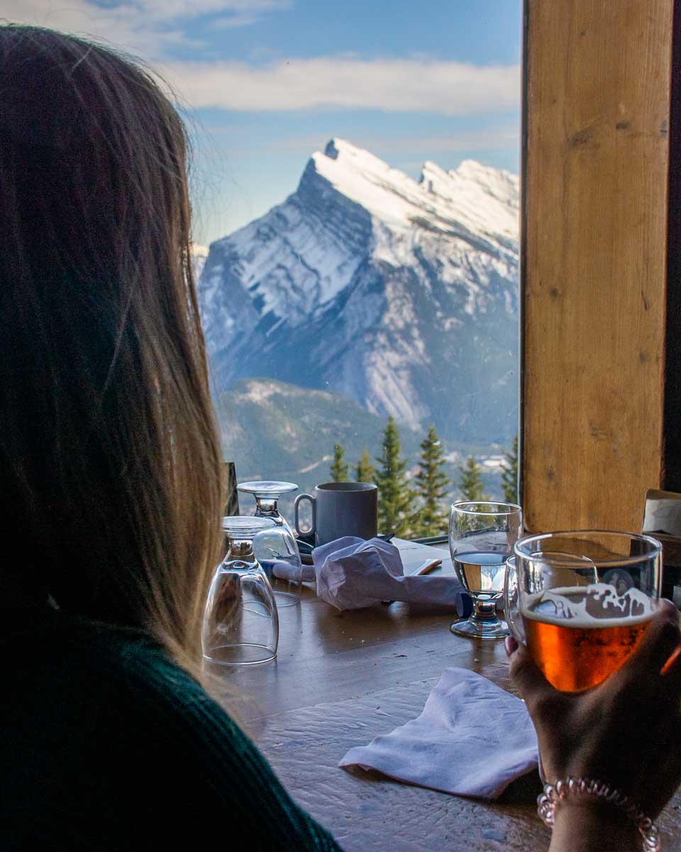 Bailey sits with a beer at the top of Mt Norquay at the Cliffhouse Bistro
