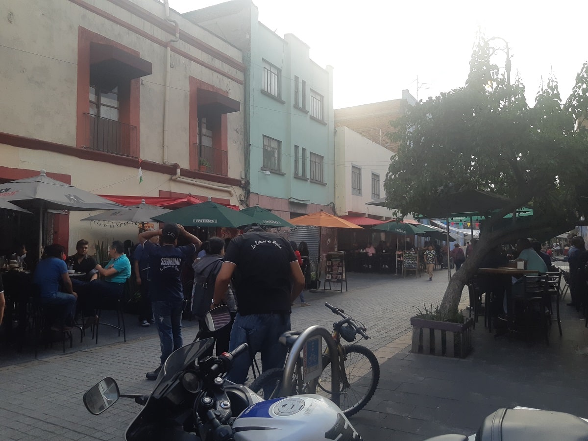 a pedestrain friendly street in Mexico City with tables and restaurants lining it