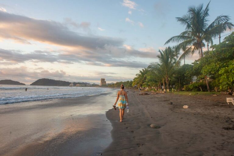 A lady walks along the beach at sunset in Jaco
