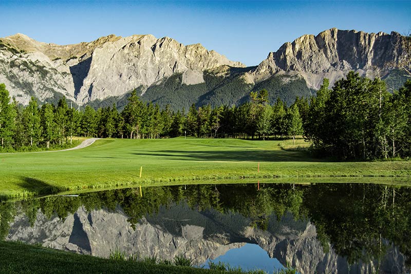 Brewsters Golf Course with a pond, the green, and mountains in the background