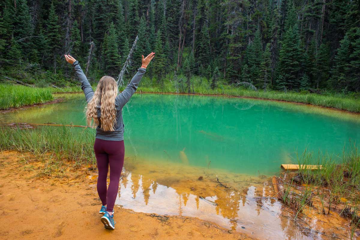 woman stands at the edge of a pond at the Paint Pots in Kootenay National Park