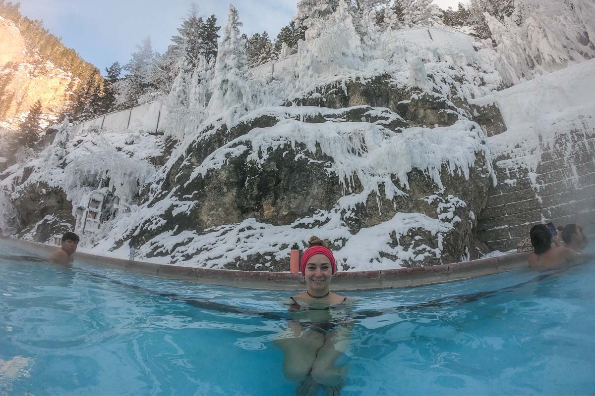 woman sits in the radium hot springs in winter