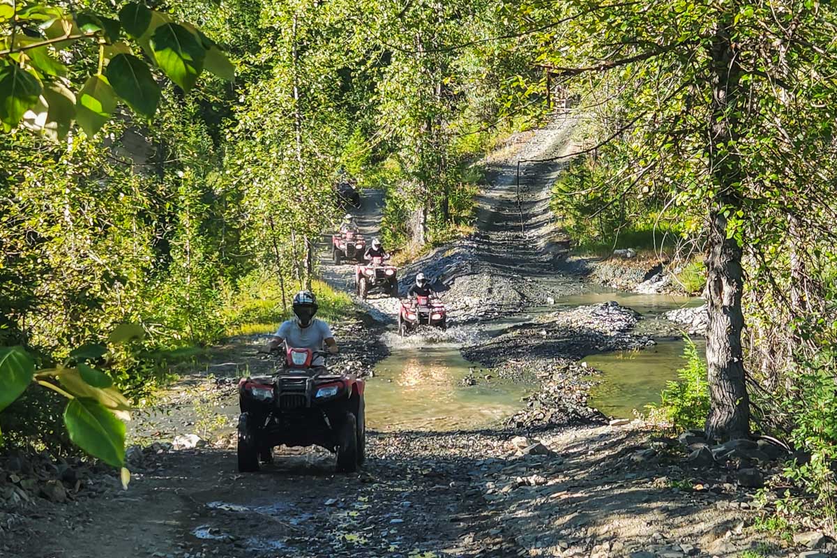 People ride an ATV through the mountains around Whistler