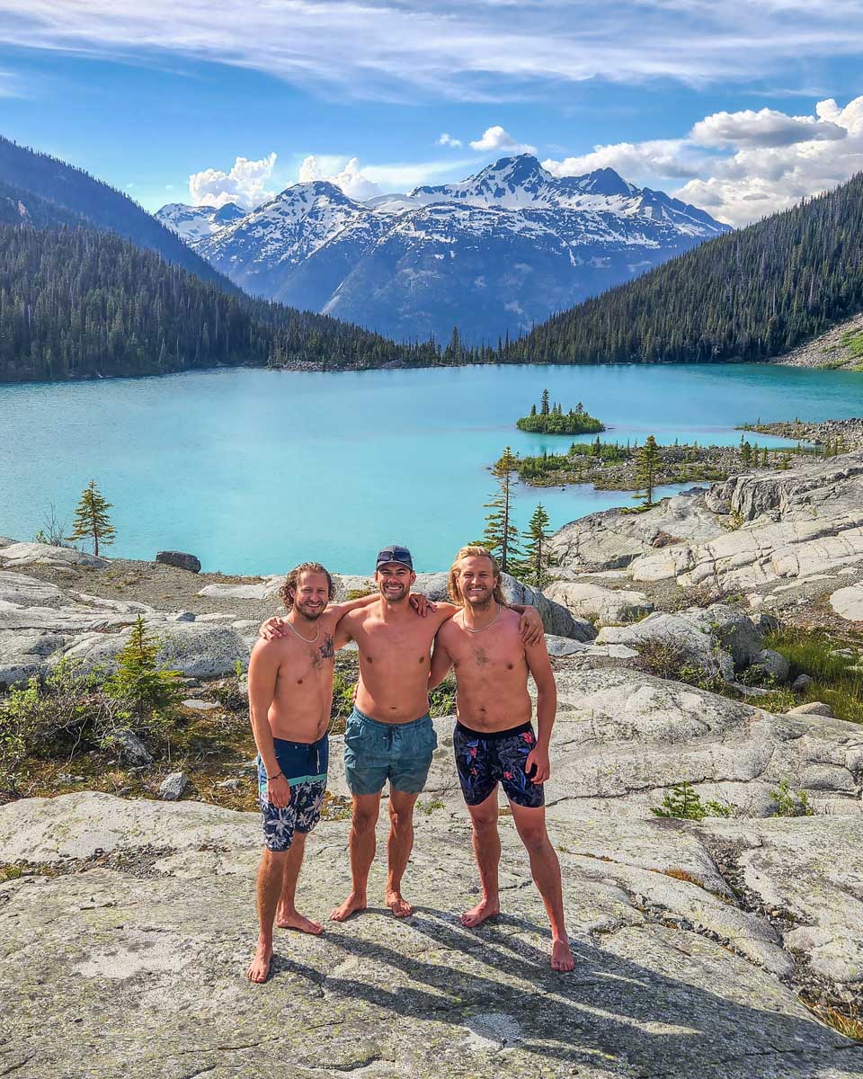 Three friends stand in the swimsuits with Joffre Lakes after a swim
