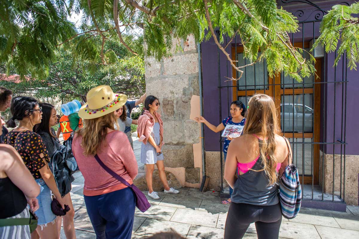 A lady explains something to a group of tourists on an historical walking tour in Oaxaca, Mexico