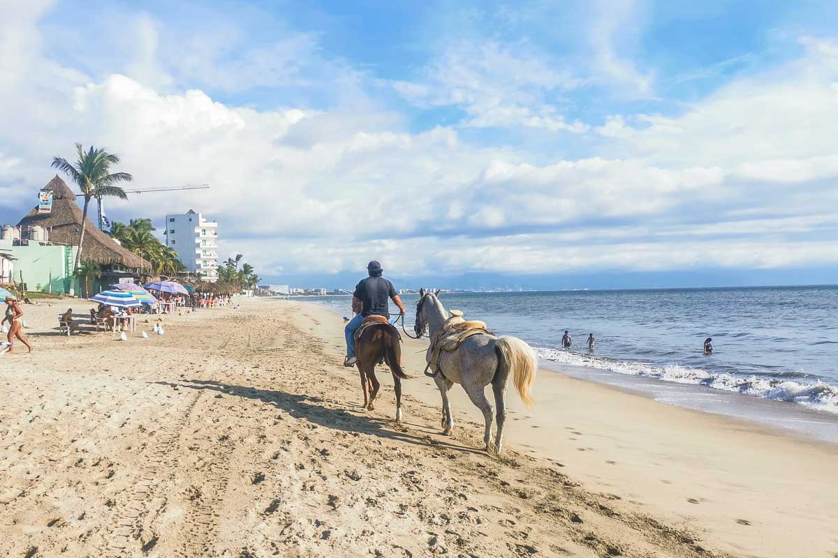 A man rides a horse aalong the beach in Bucerias, Mexico