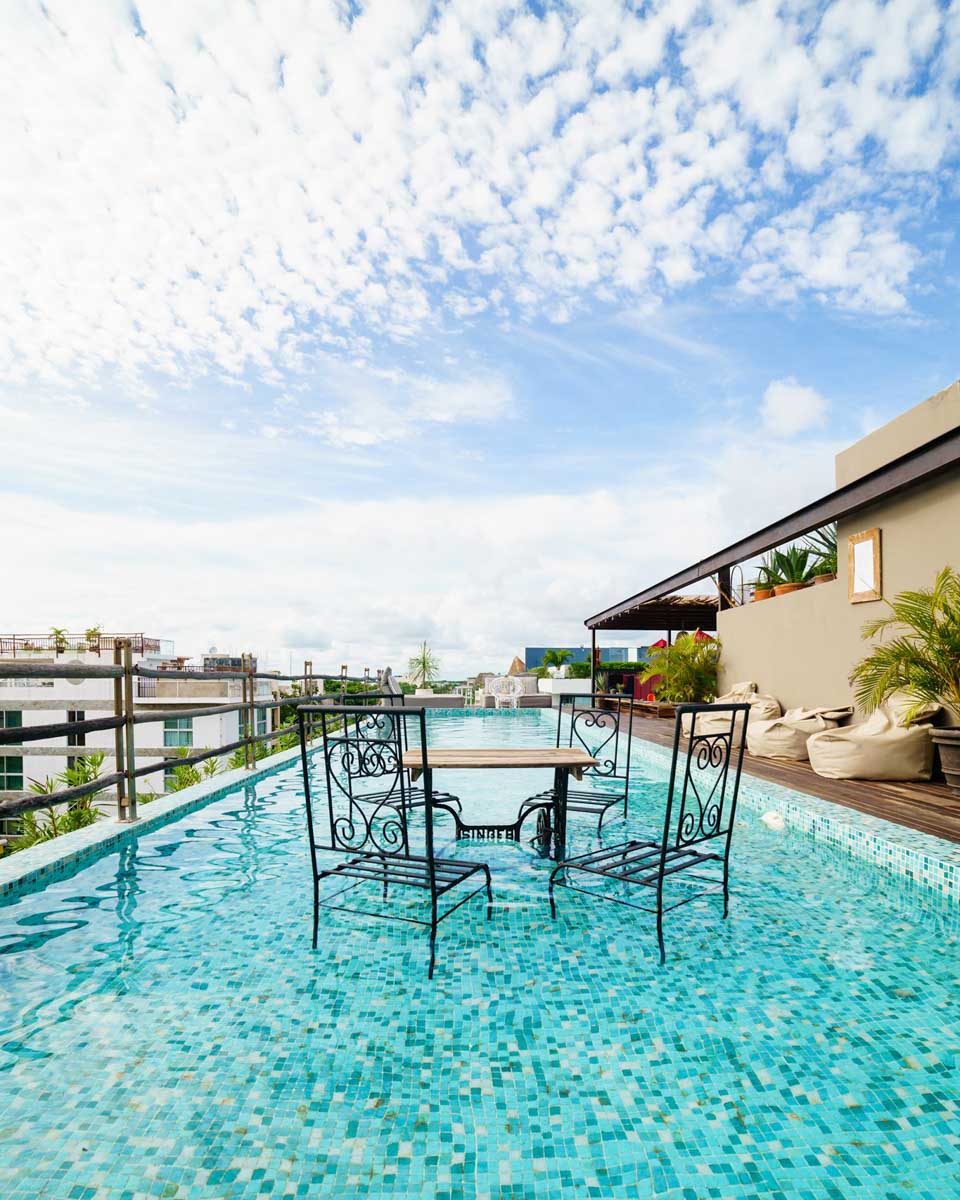 Two chairs and a table sit in the pool at Be Playa Rooftop Pool in Playa del Carmen, Mexico