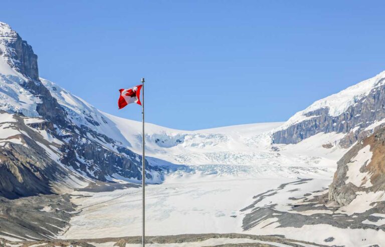 A Canadian Flag on a pole with the Athbasca Glacier in the background as seen from the Columbia Icefield Glacier Adventure
